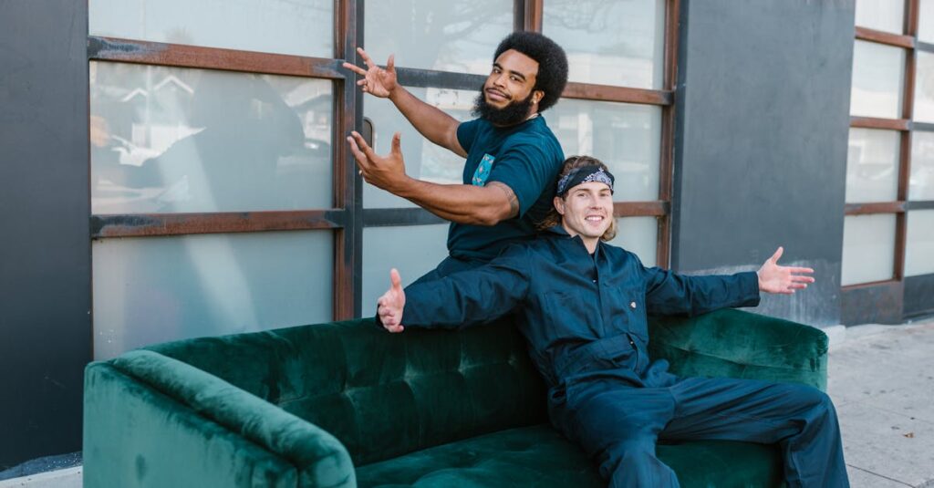 Two movers taking a break on a green sofa outside an urban building, enjoying the day.
